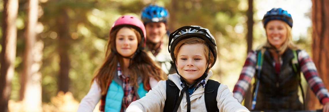 Zwei Kinder und zwei Erwachsene fahren Fahrrad im Wald